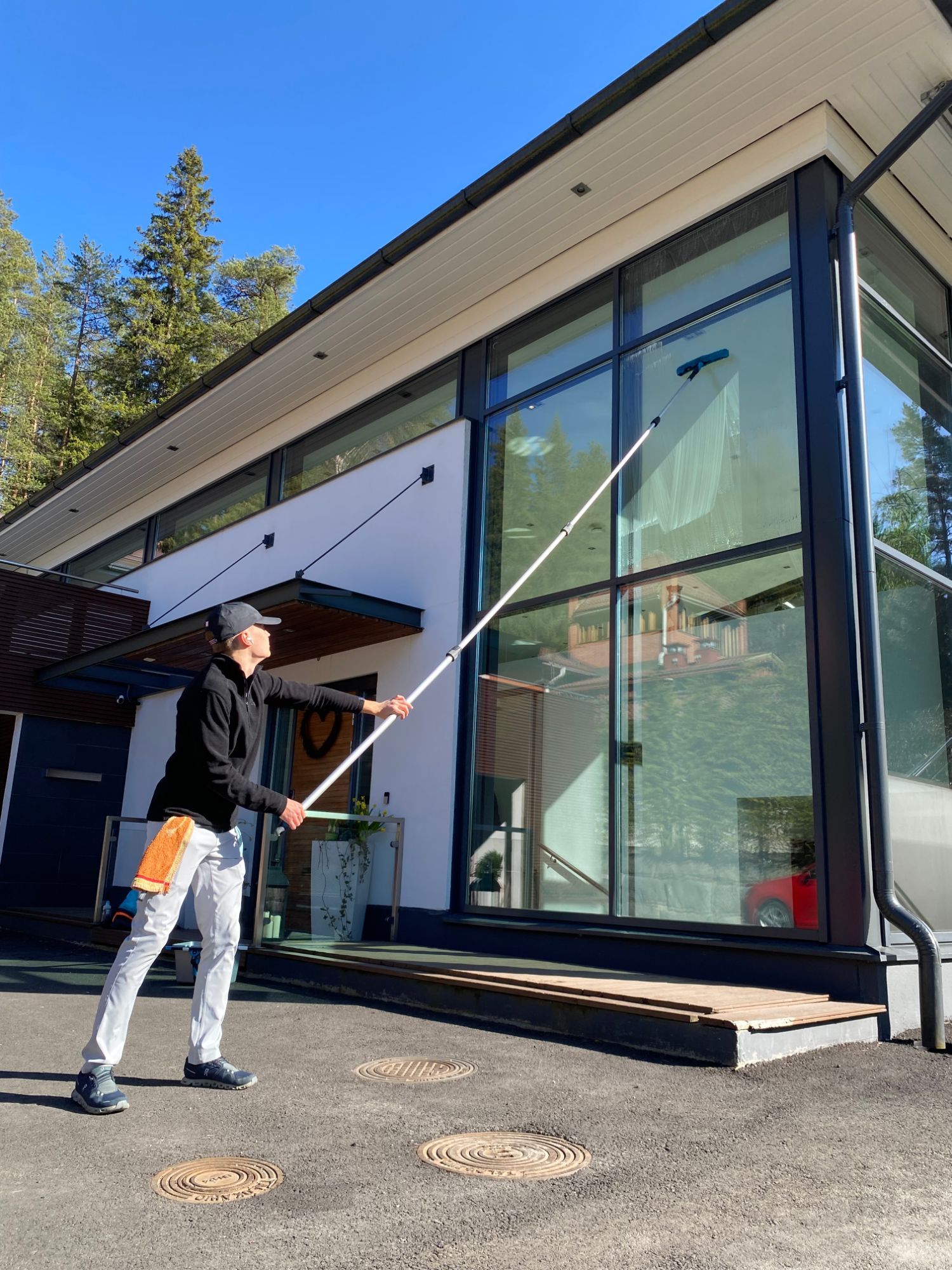PB & Co:n perustaja pesee kaksikerroksisen talon lasiseinää jatkovarrella.